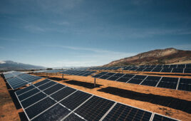 A photo of a single-axis solar tracker project installed on an uneven plot of arid land.