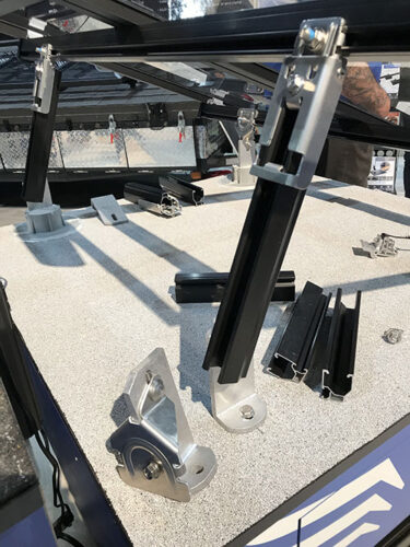 Loose pieces of solar rail and mounts rest on a table next to a single assembled solar array.