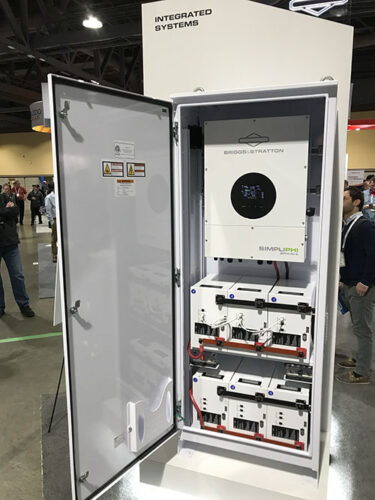 An inverter tied to several batteries is installed inside a rectangular metal box with a door.